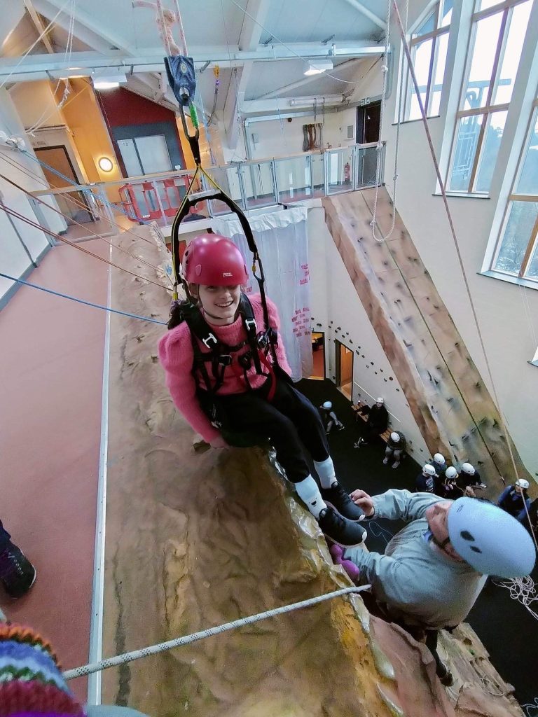 Ella a guest is Bendrigg Trust is rock climbing whilst sitting in the Chunc wheelchair